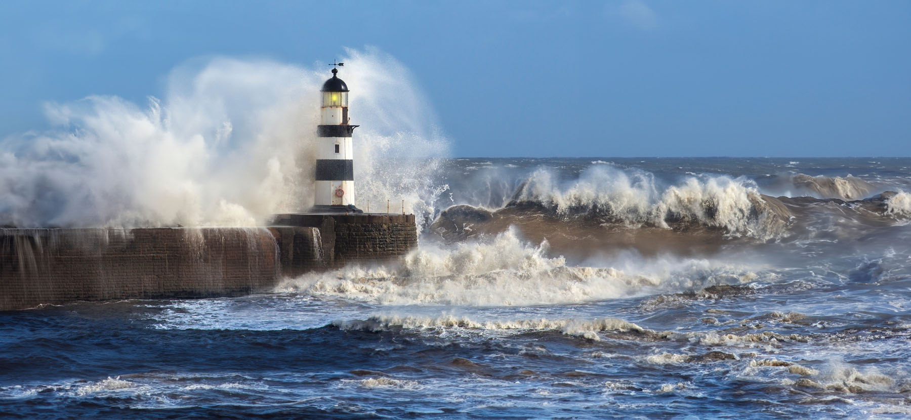 waves crashing onto lighthouse